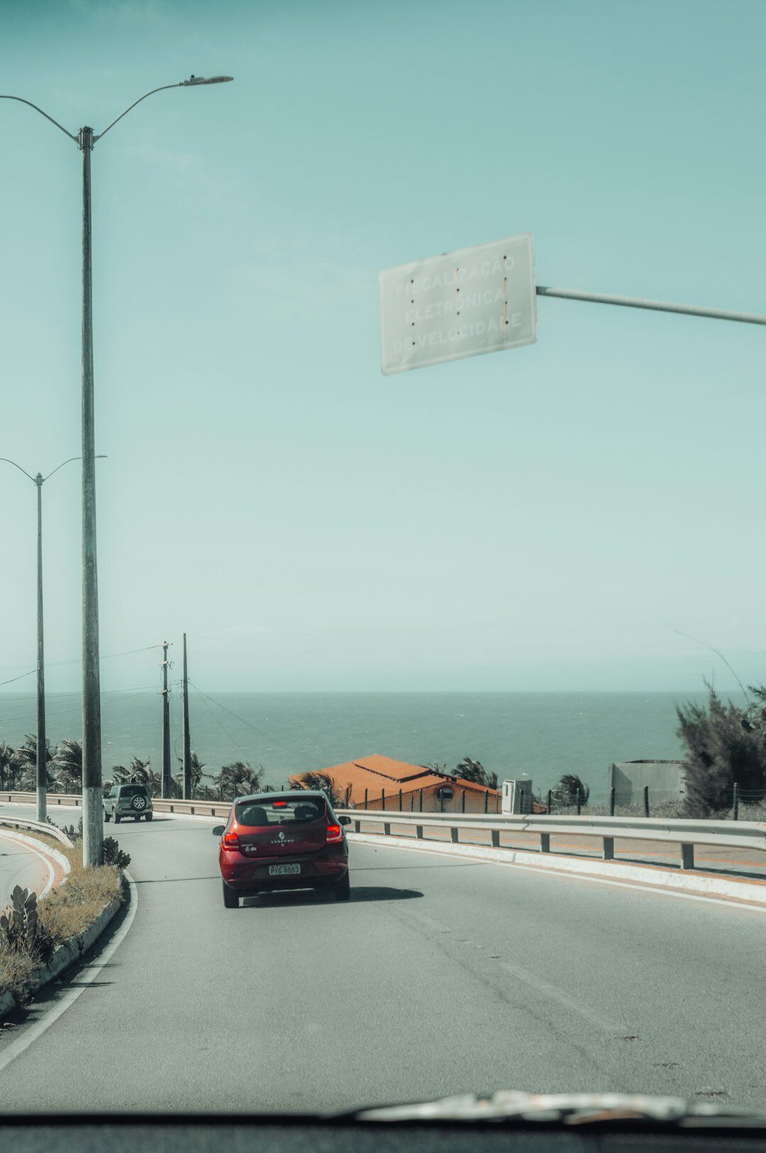Luxury sedan driving along a coastal road in Punta del Este at sunset